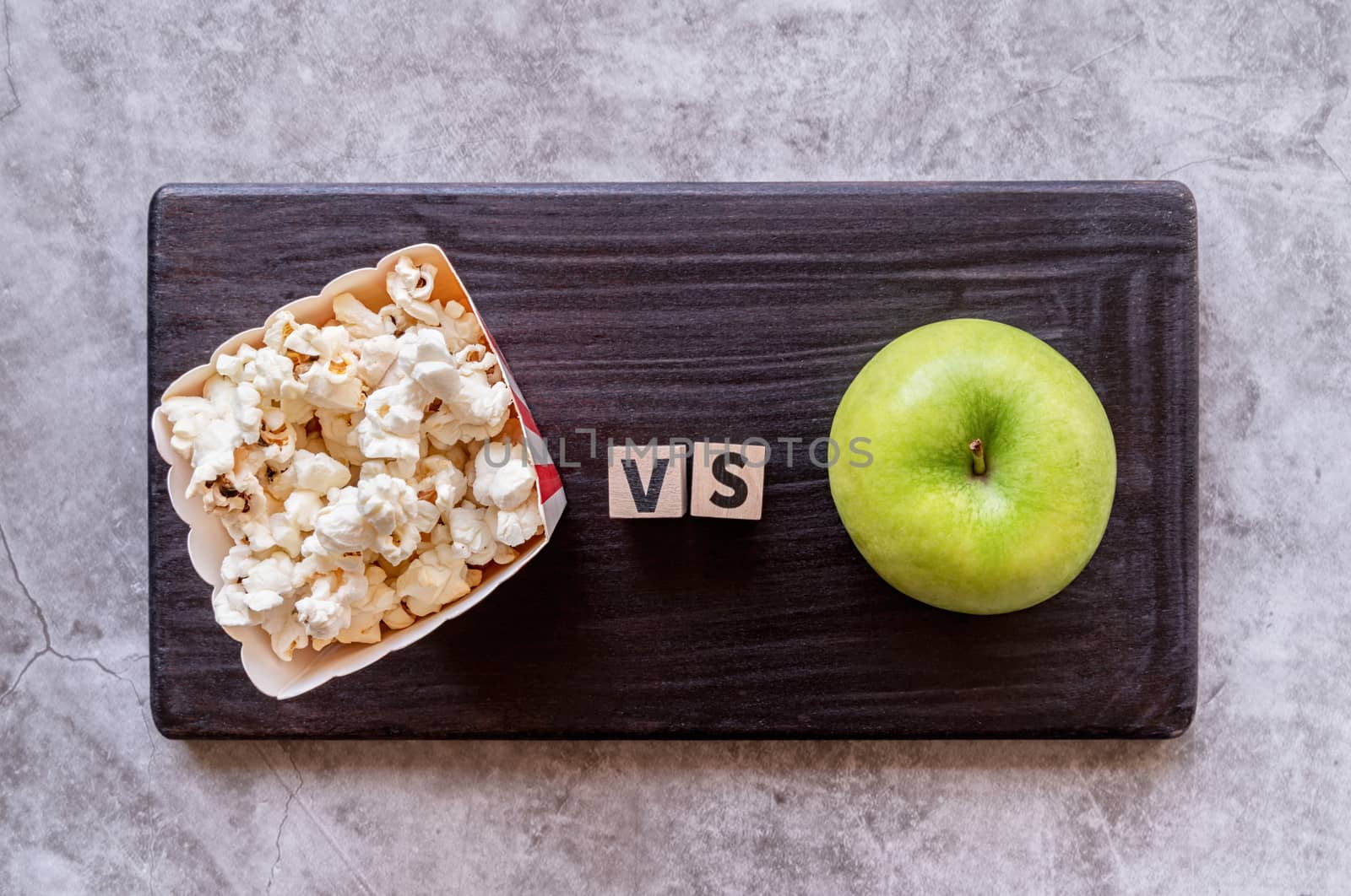 pop corn versus apple top view on dark background by Desperada