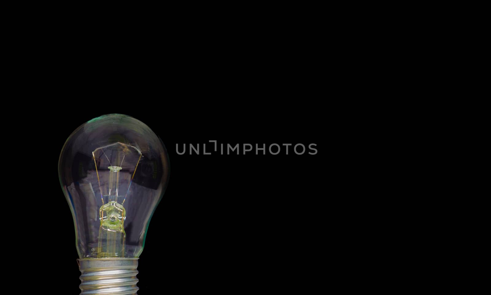 A light bulb on a black background to place text or illustration. The light bulb is a symbol of ideas, innovations, and new thoughts. 220 volt. Light bulb, business idea concept.