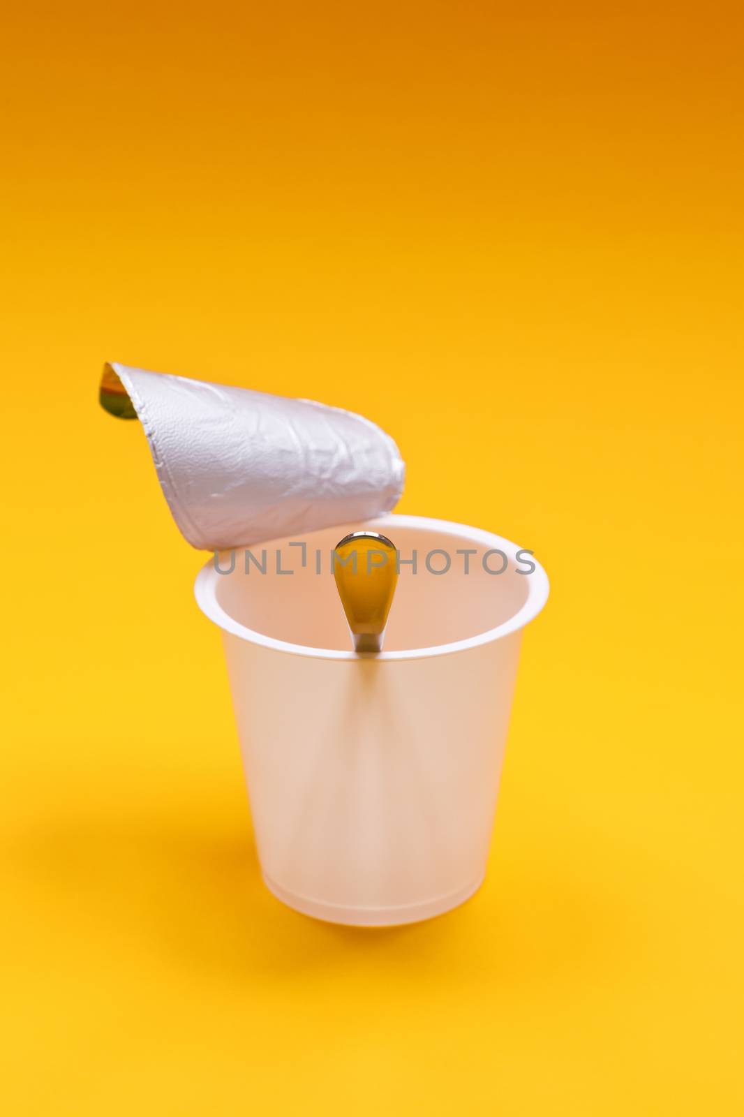 empty clean yogurt cup with spoon on an orange background by magann