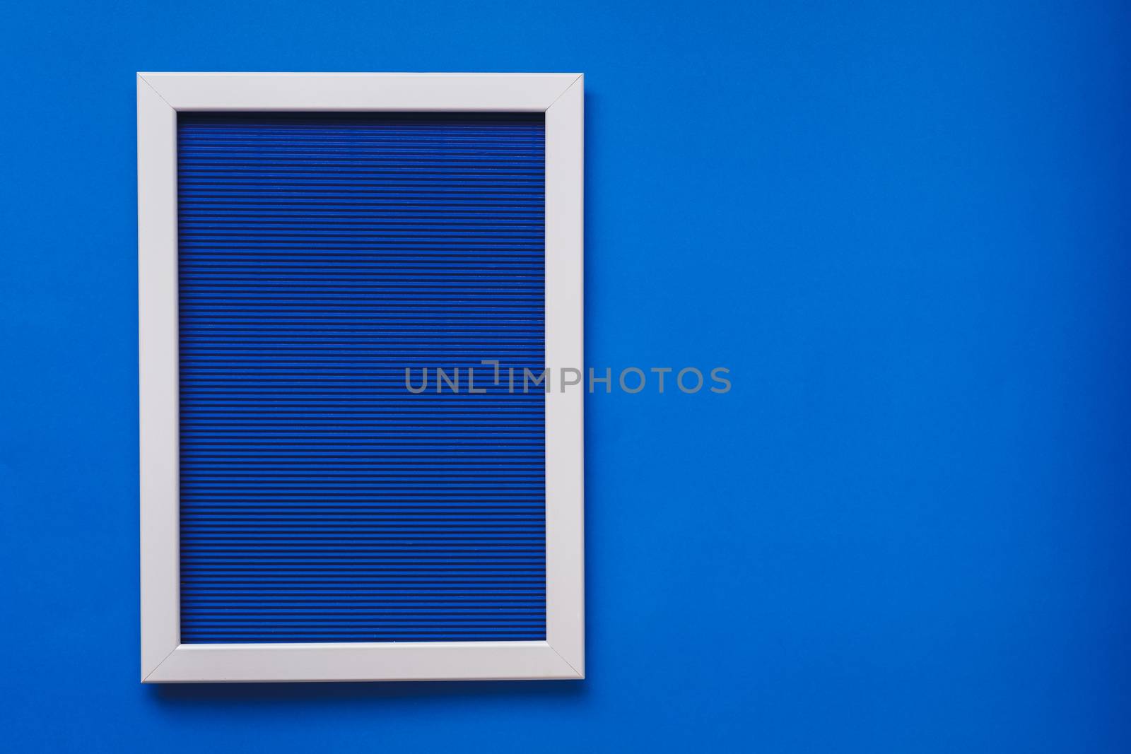 Empty  white frame on blue pattern texture of crumpled paper in the volume of horizontal lines hanging on blue wall by Slast20