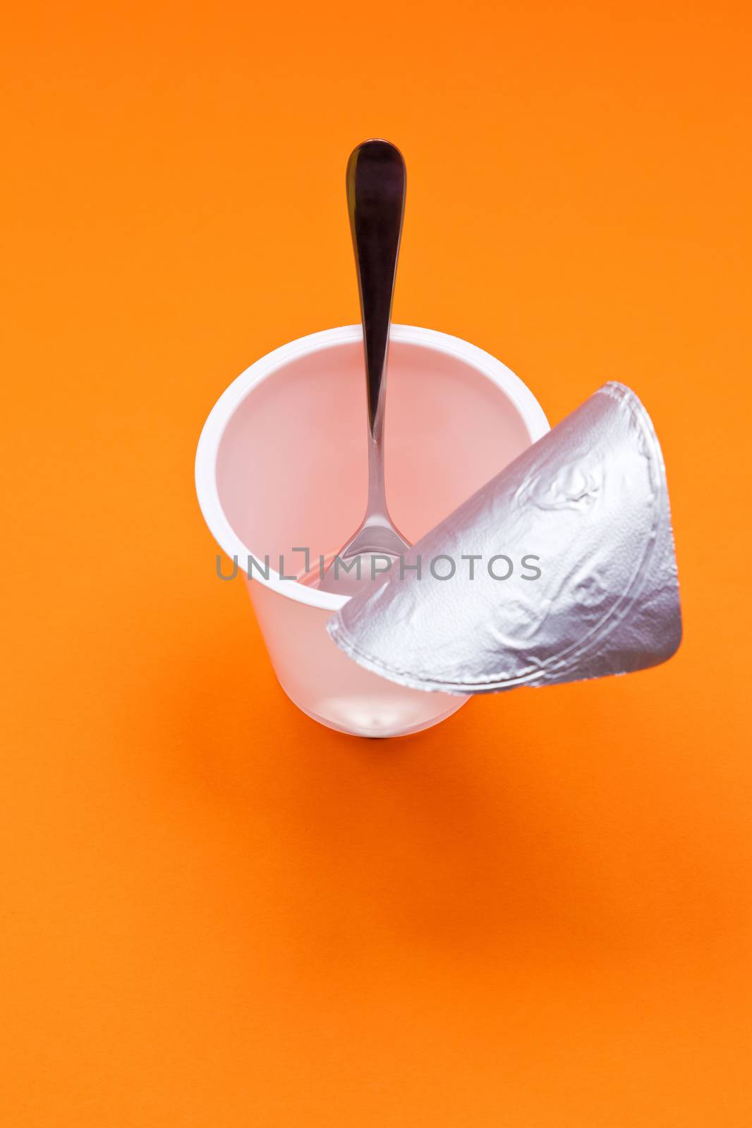 empty clean yogurt cup with spoon on an orange background by magann