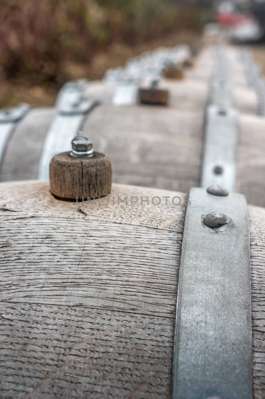 Macro photograph of small vintage grey wooden wine barrels in a long row in winter season. Shot in daylight at St. Claire's Vineyard, Botanical gardens in Prague.