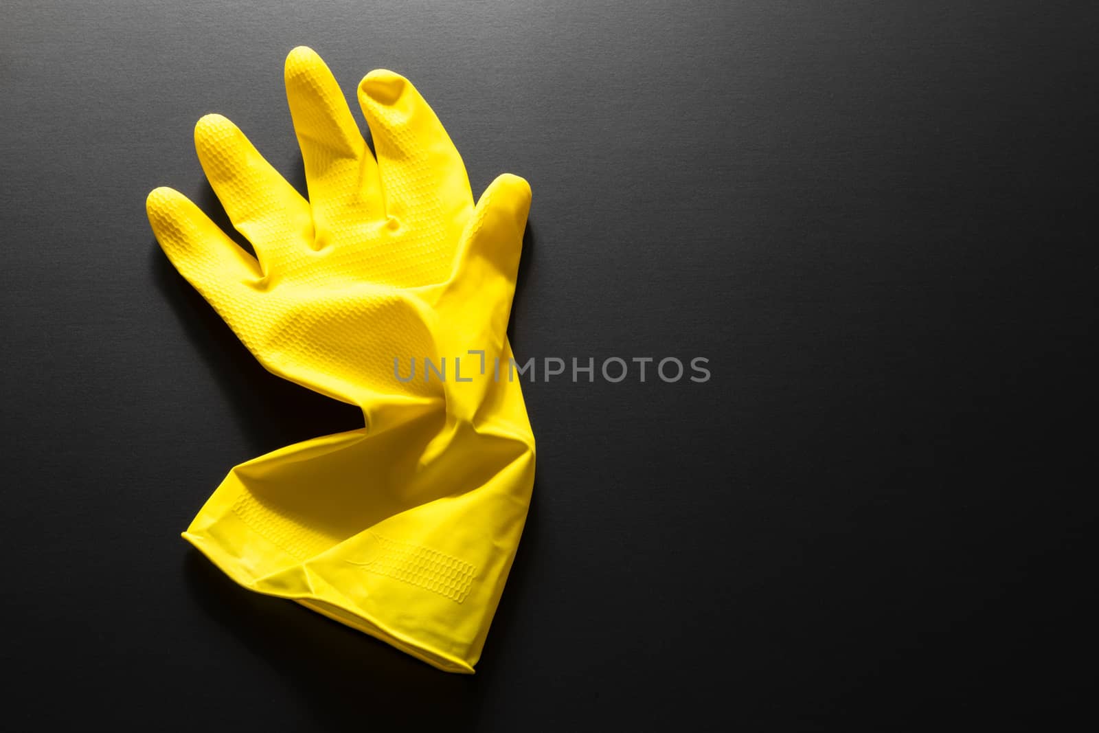 An image of a yellow rubber glove isolated on black background