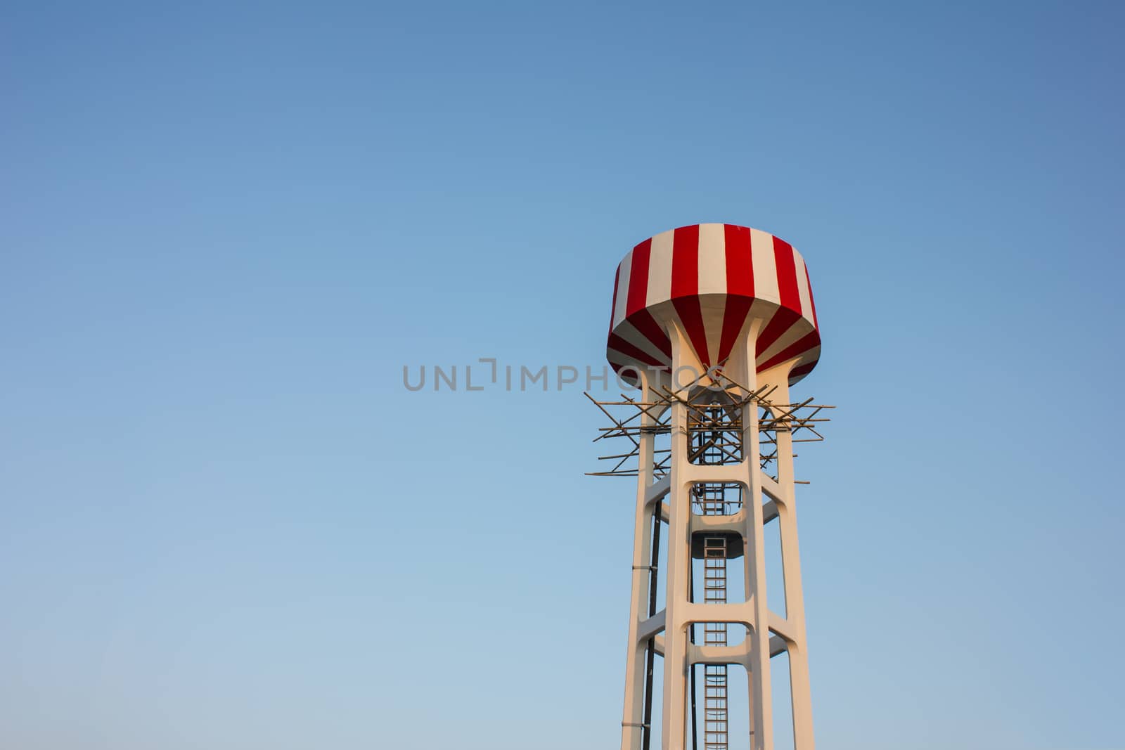 Water tower with red and white stripes (blue sky background)