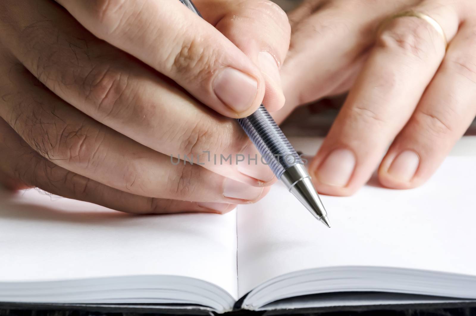 The right hand of a man writing with a pen on a notebook with blank pages. Journalistic or creative activity. White pages. Waiting for the right inspiration