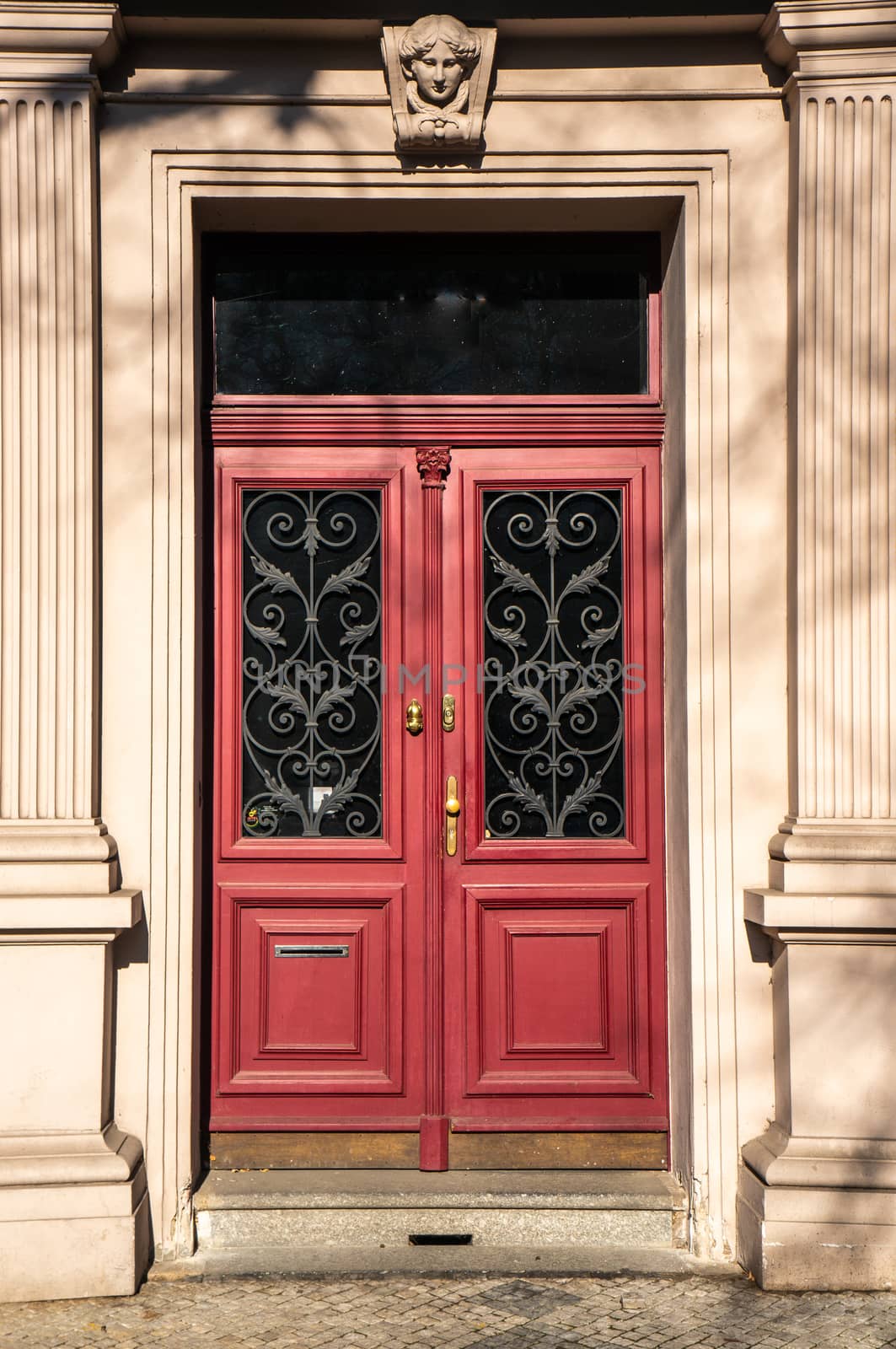 Classical European doorway with stone pillars around red door by sara_lissaker