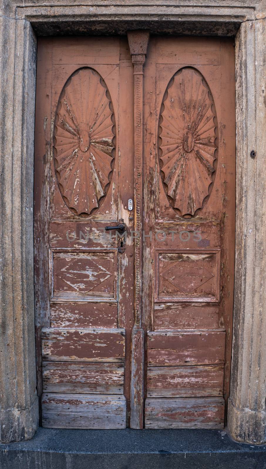 Worn out ornate brown doorway with paint chipping away by sara_lissaker