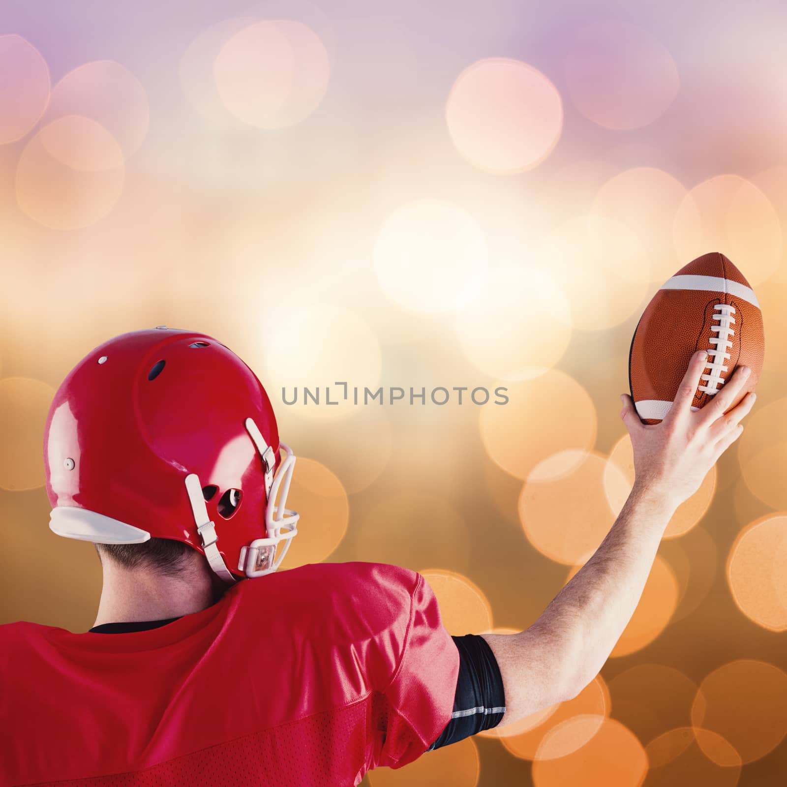 Rear view of american football player holding up football against blue glowing background