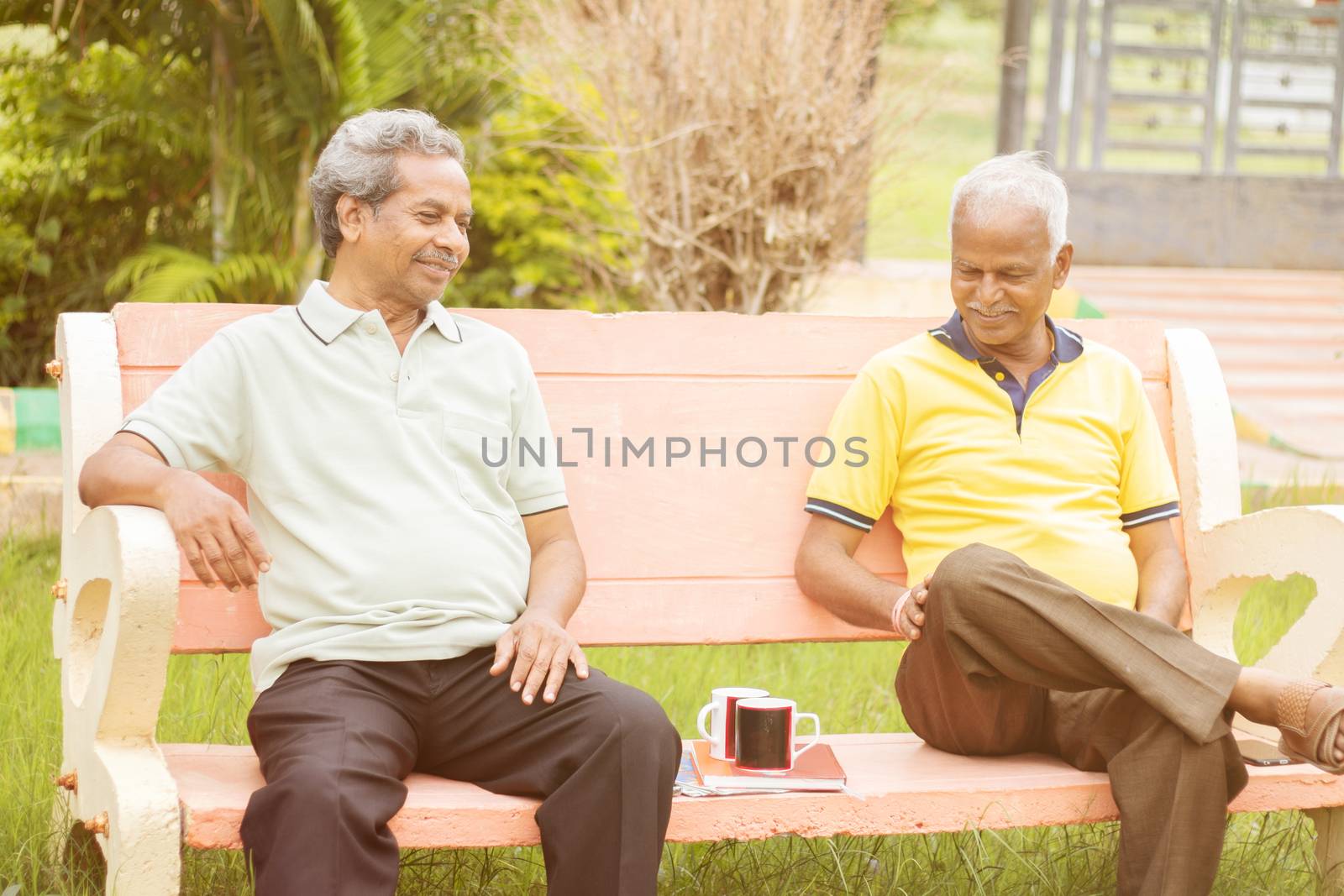 Active retired old men and leisure concept - two senior friends talking outdoor during evening time with coffee - Two elderly brothers having happy time
