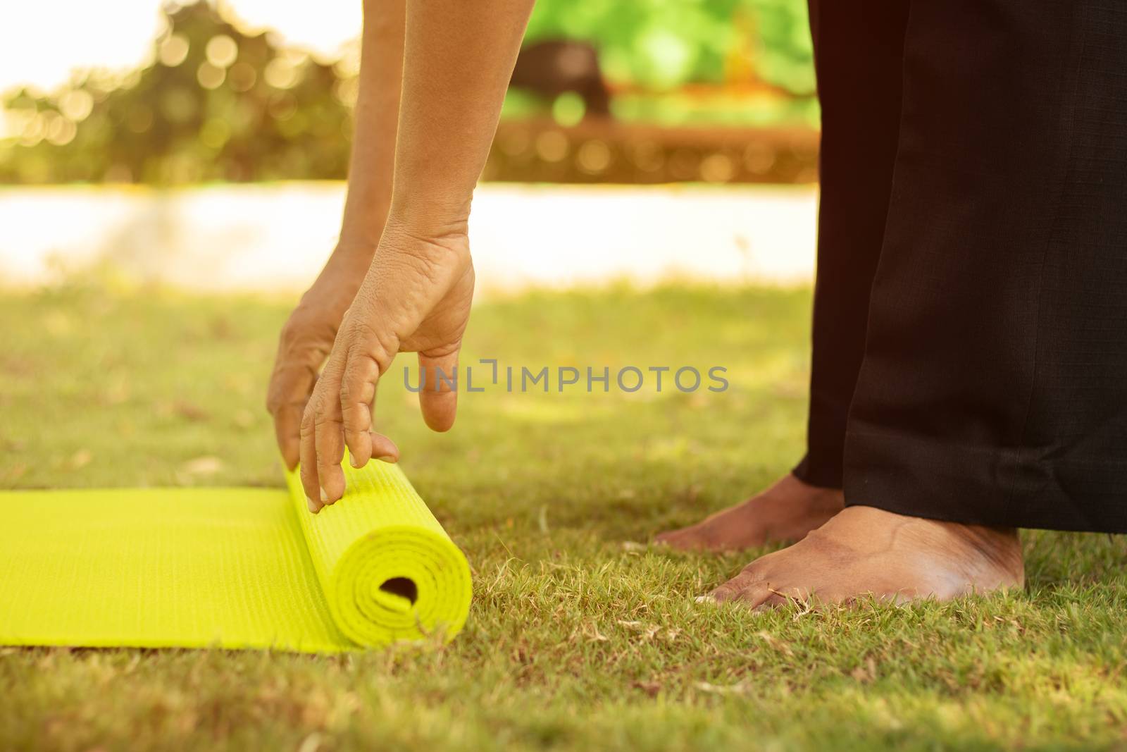 Practicing yoga or pilates outdoors - Senior man hands preparing yoga mat at park - close up, getting ready to do yoga on mat