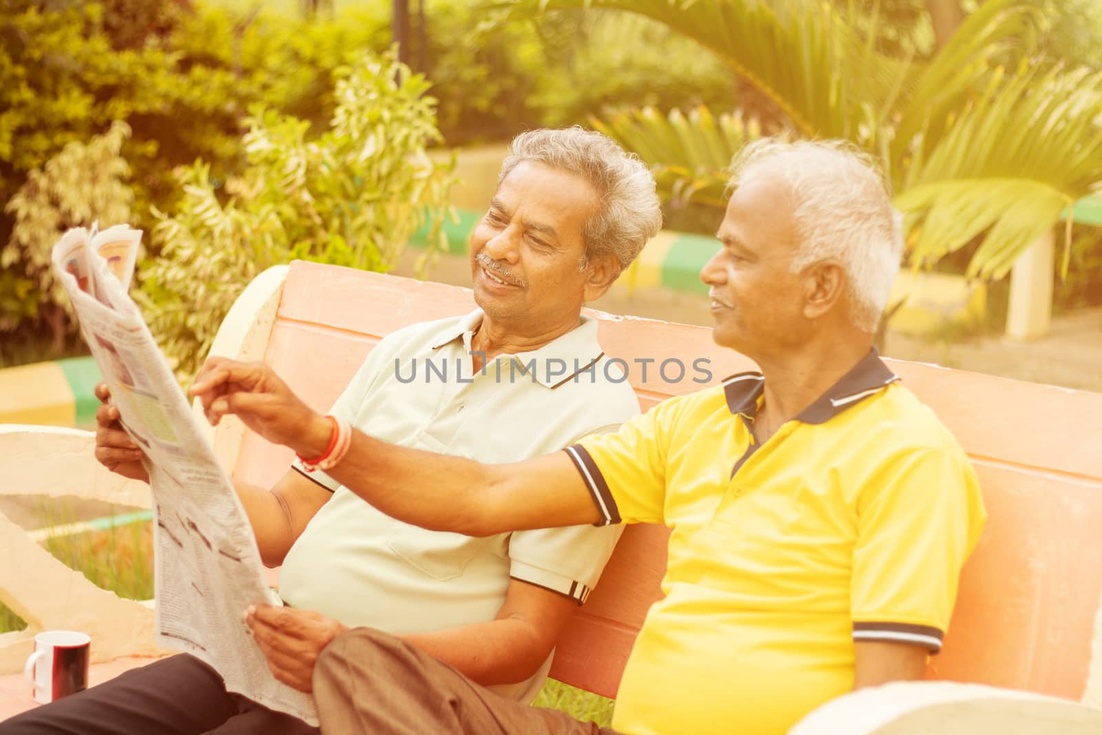 Two happy senior men reading newspaper at park outdoor - elderly friends enjoying moring news - Concept of happy older men lifestyle. by lakshmiprasad.maski@gmai.com