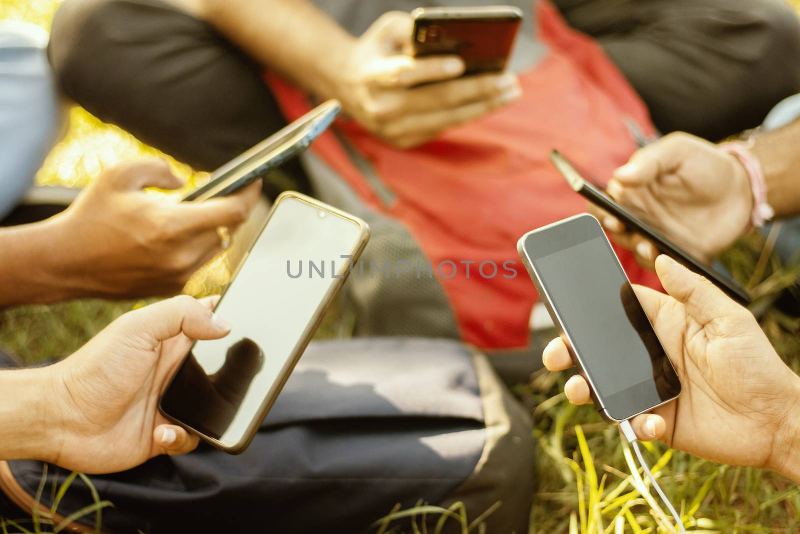 Selective focus on Hands, Close up of young people hands holding mobile - College Students addicted to smartphone - young millennials busy on cell phone - Group of friends sharing content on social media. by lakshmiprasad.maski@gmai.com