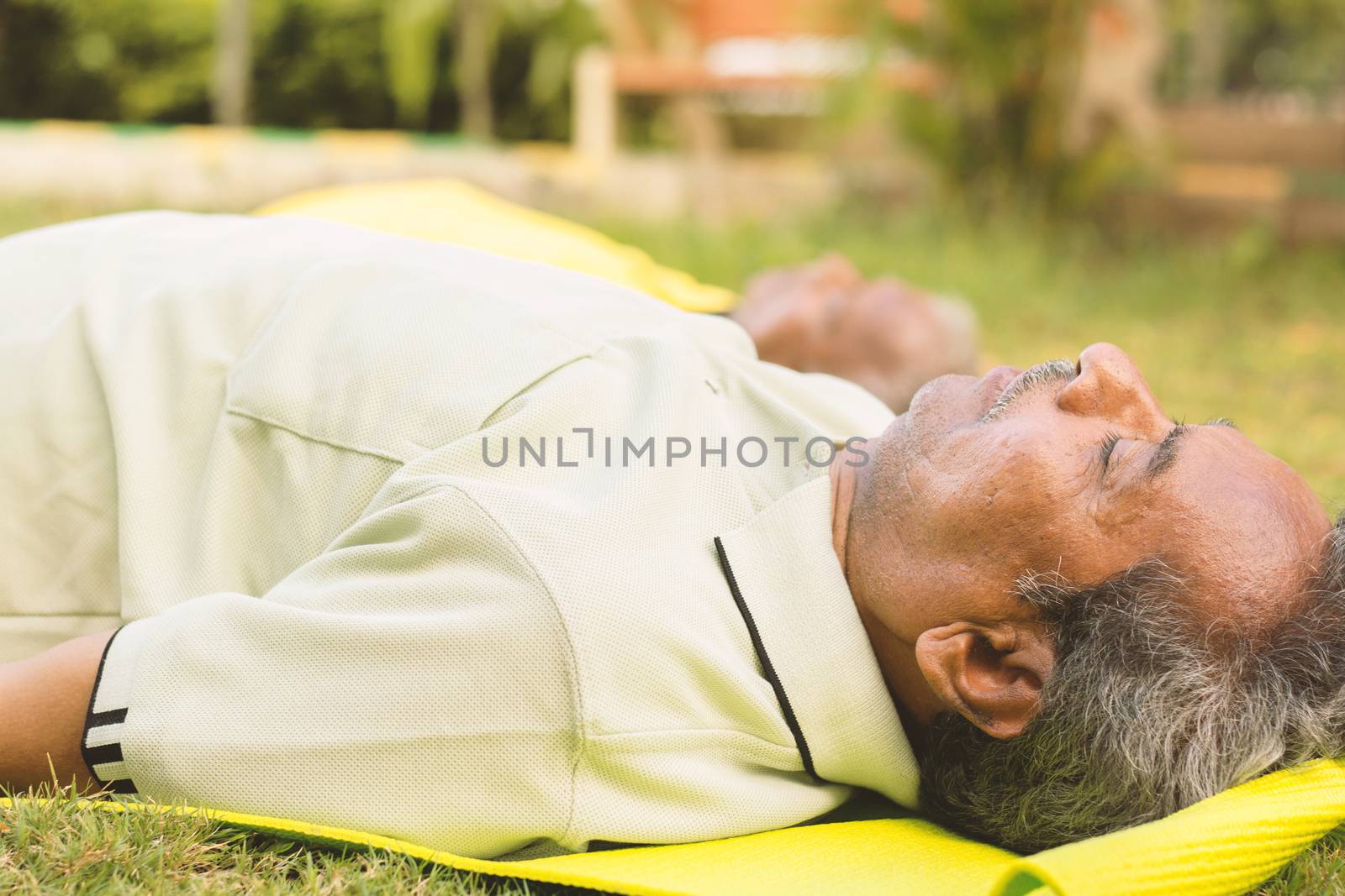 Old men practicing in a yoga - Shavasana or corps pose is the end of a class or practice - yoga for senior people, active healthy elderly concept