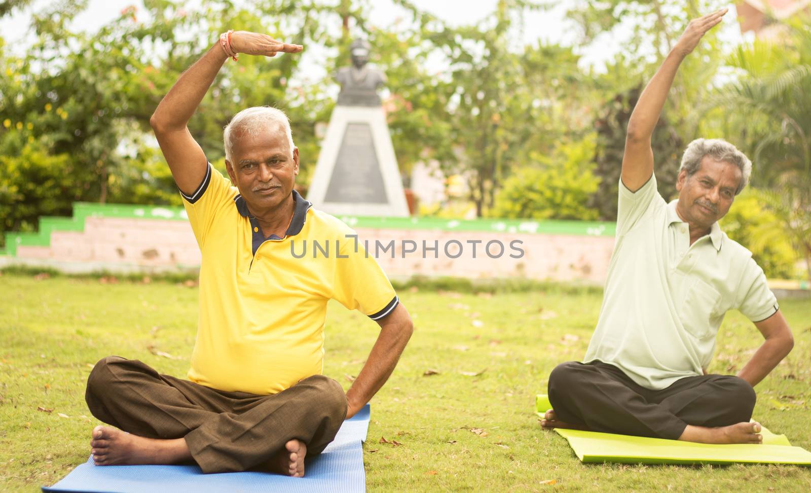 Happy senior people doing yoga by stretching hands - Concept of Senior people fitness and healthy lifestyle - two elderly man busy in morning exercise.
