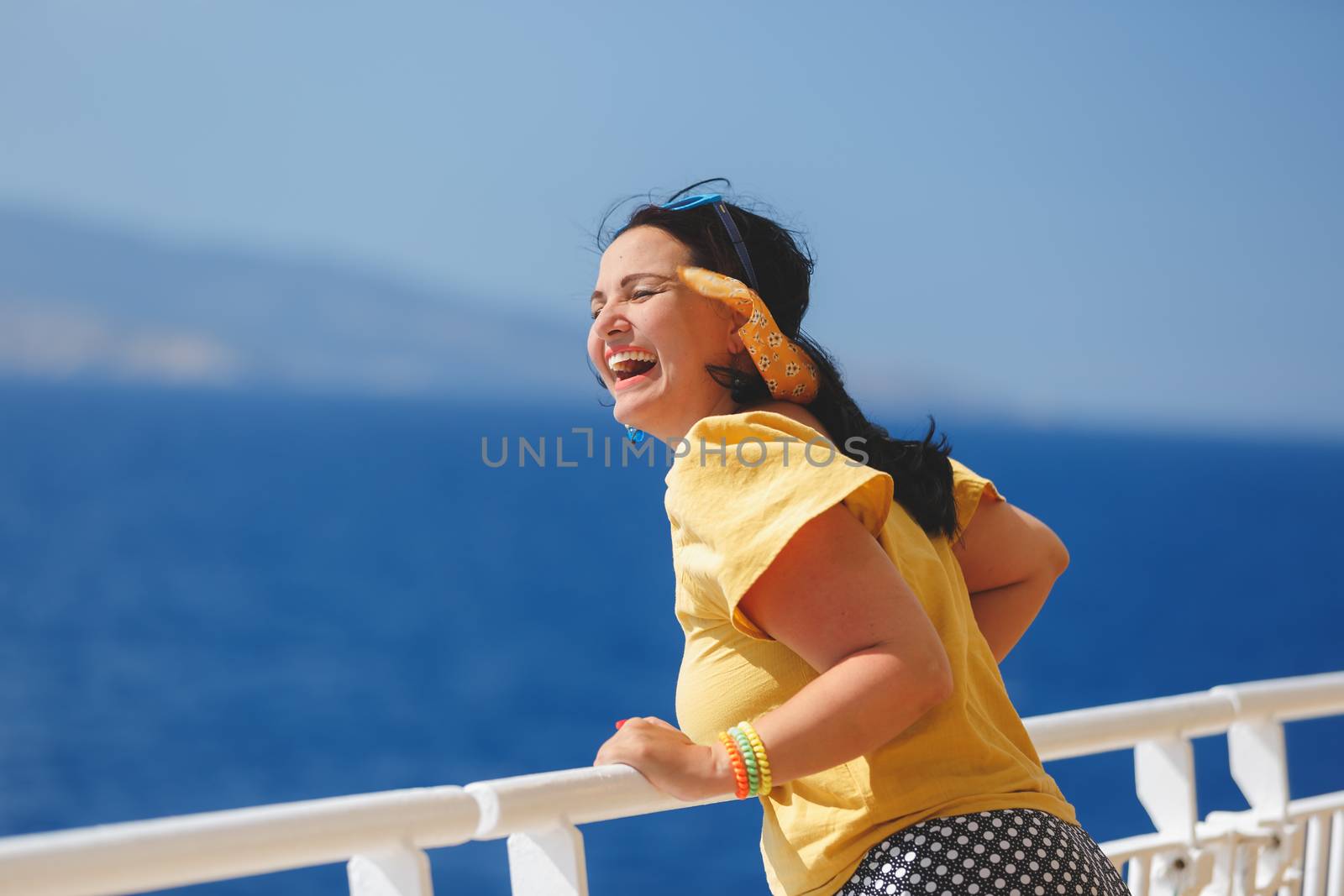 Happy Woman On A Cruise Vacation. standing on deck of cruise ship, strong wind blowing her hair