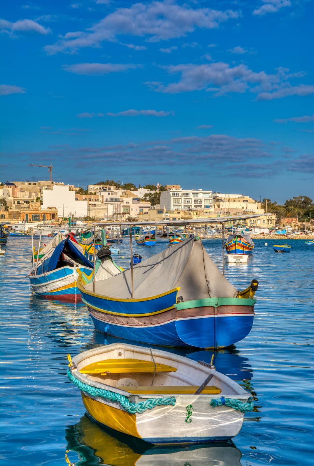 Marsaxlokk, Malta - January 10, 2020: Beautiful view of the traditional eyed colorful boats Luzzu in the Harbor of Mediterranean fishing village Marsaxlokk, Malta