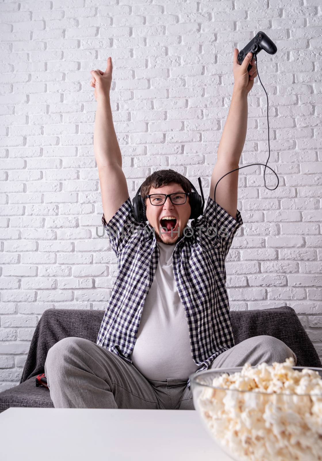 Excited young man playing video games at home enjoying his victory by Desperada