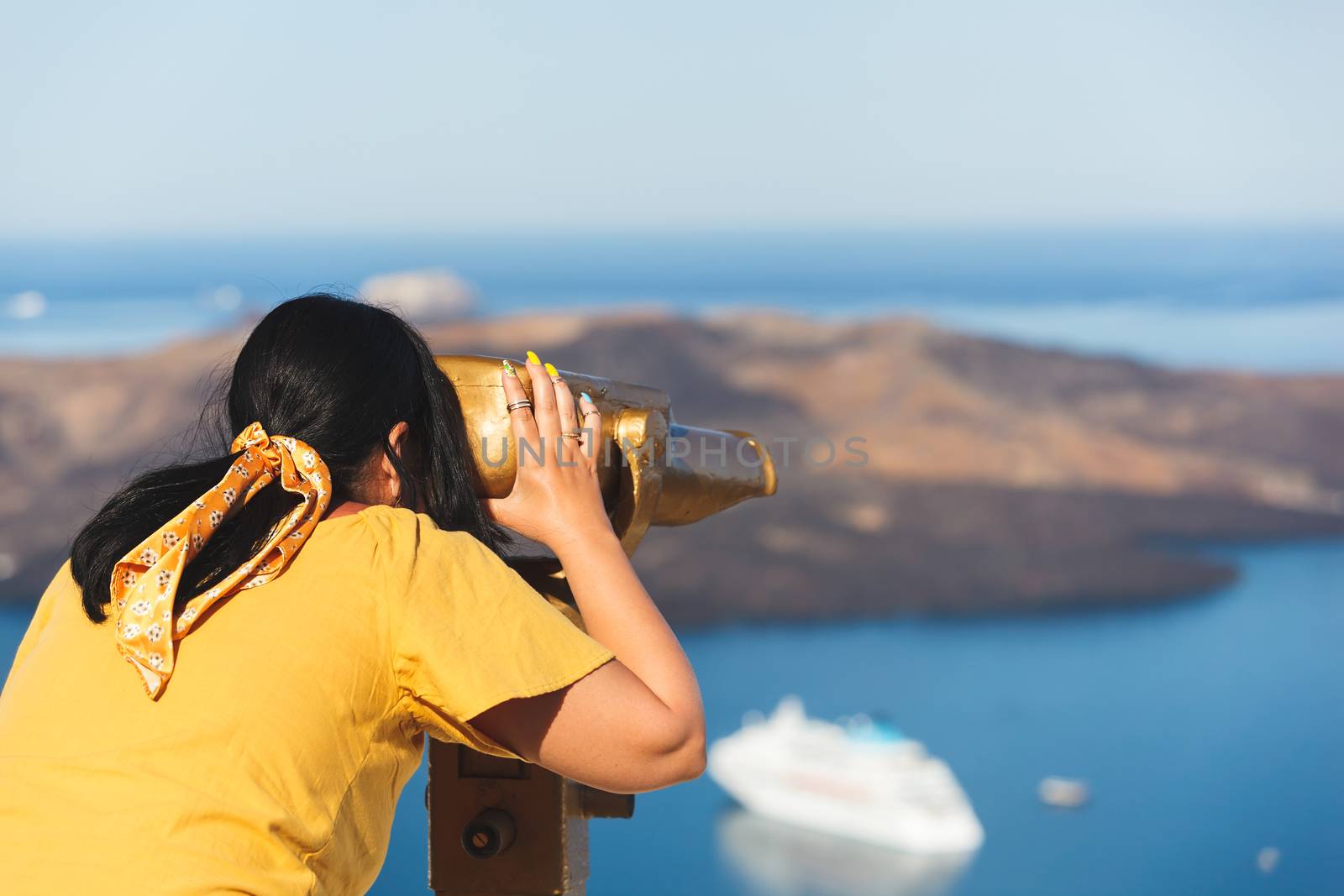 Beautiful young woman looking at cruise ships with binoculars in Thira, Santorini, Greece  enjoying vacation, selective focus by Slast20