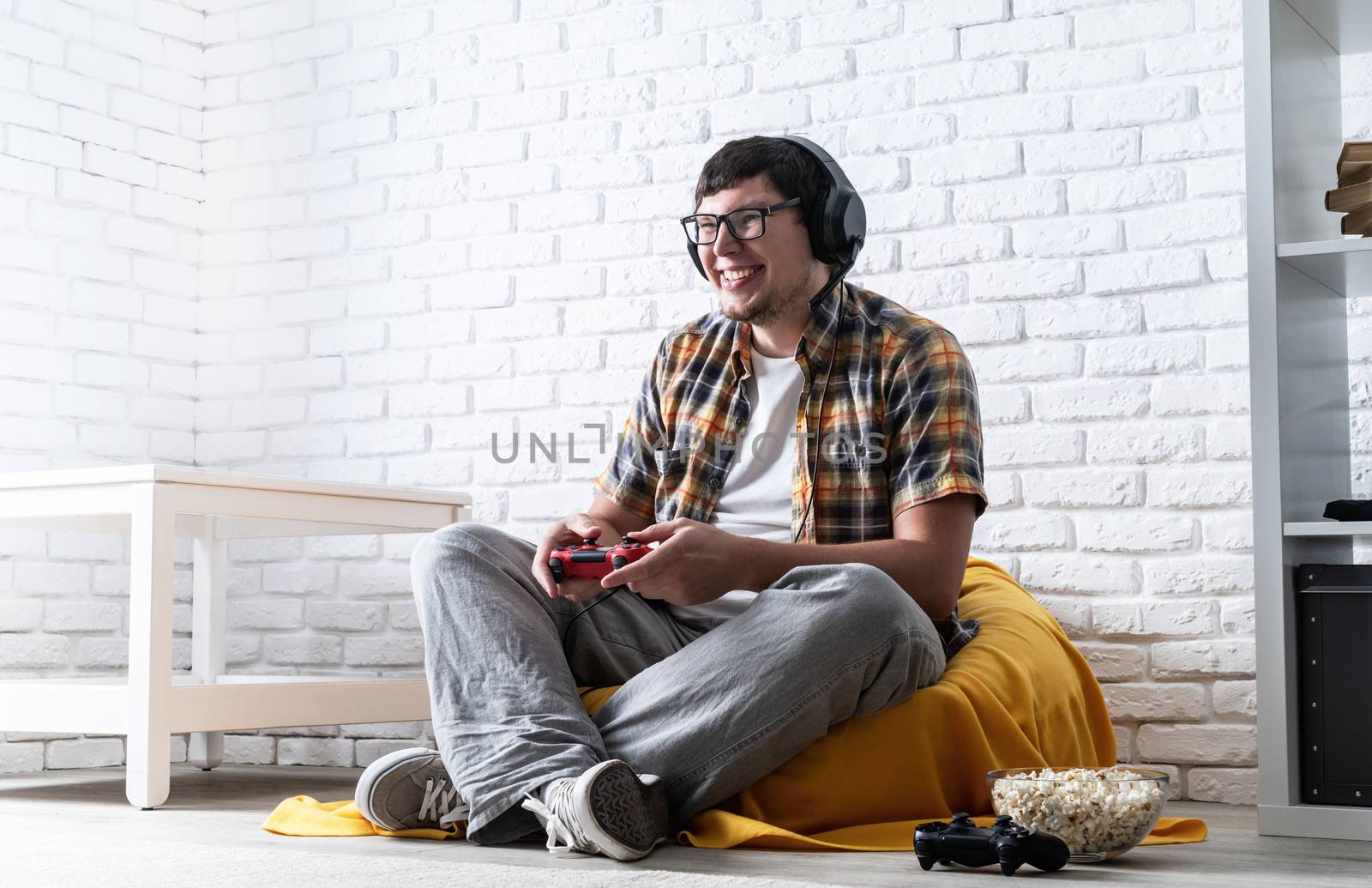 Excited young man playing video games at home and laughing by Desperada