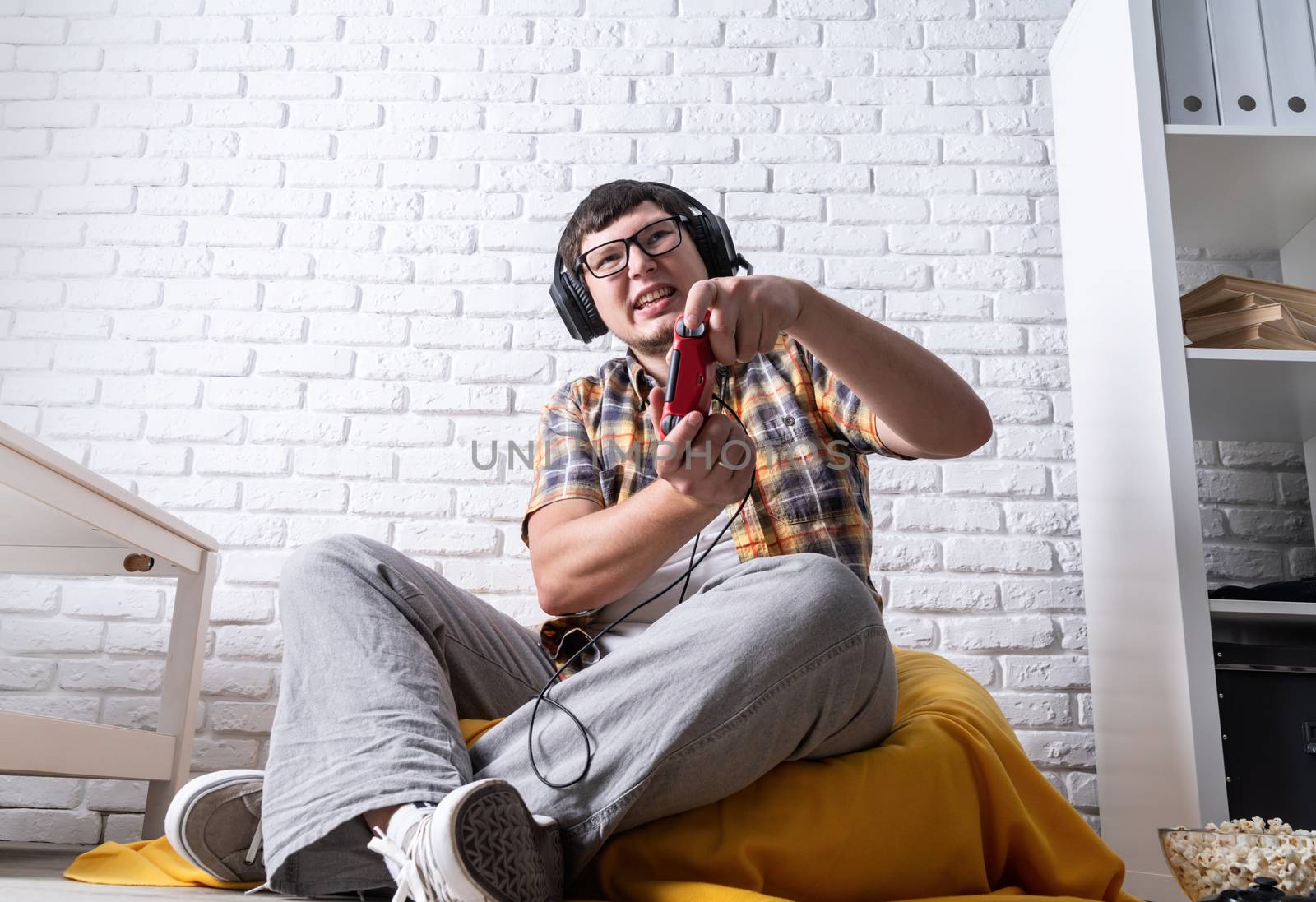Young man playing video games at home by Desperada