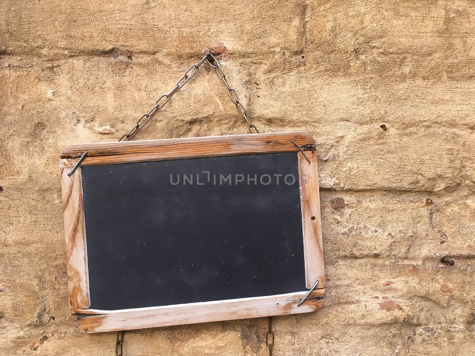 Blackboard with wooden frame on old wall.