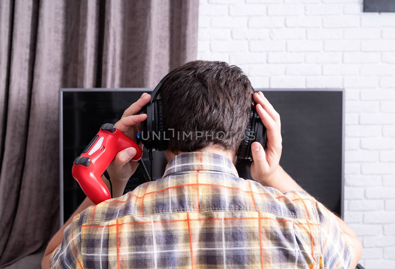 Stay home. Rear view of a young man playing video games at home