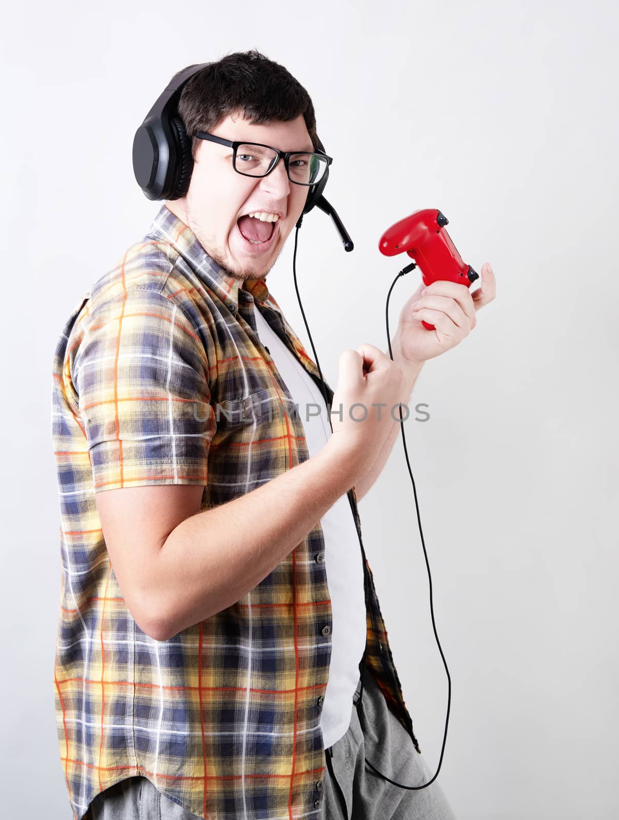 Excited young man playing video games holding a joystick isolated on gray background by Desperada