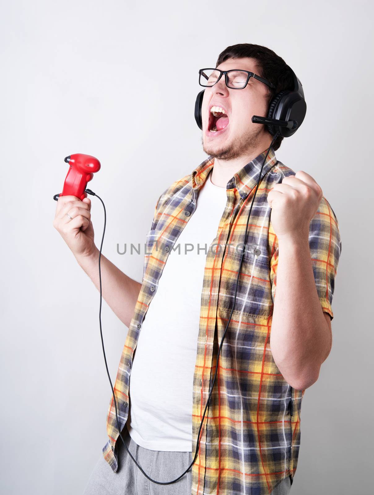Stay home. Funny young man screaming playing video games holding a joystick isolated on gray background