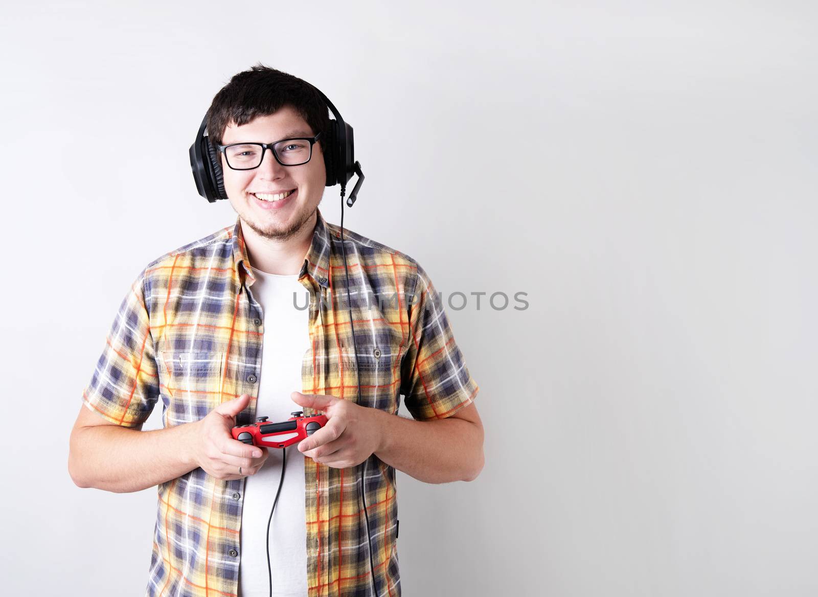 Smiling young man playing video games holding a joystick isolated on gray background by Desperada
