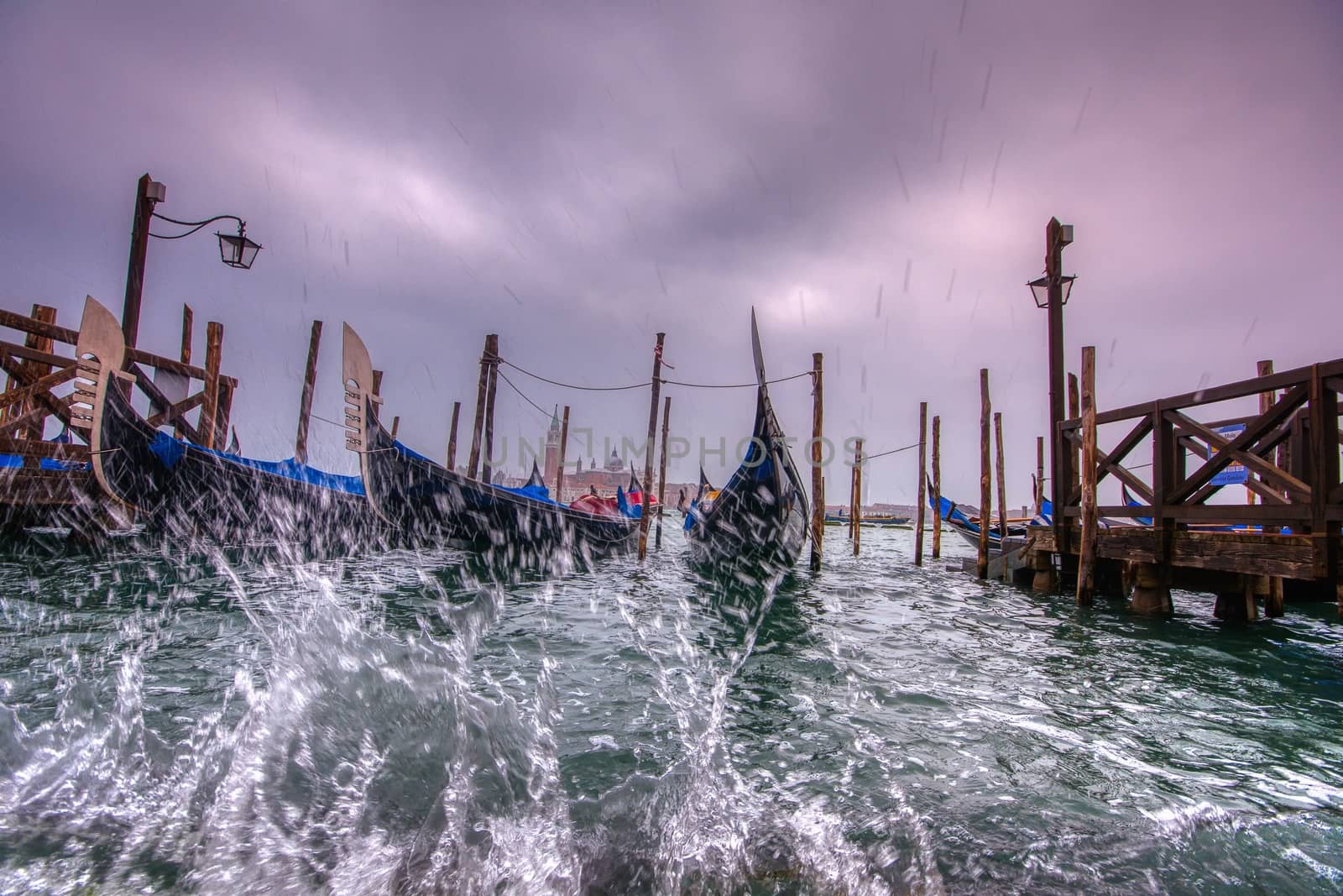 Gondolas parked at San Marco square with high tide and waves, Venice, Italy