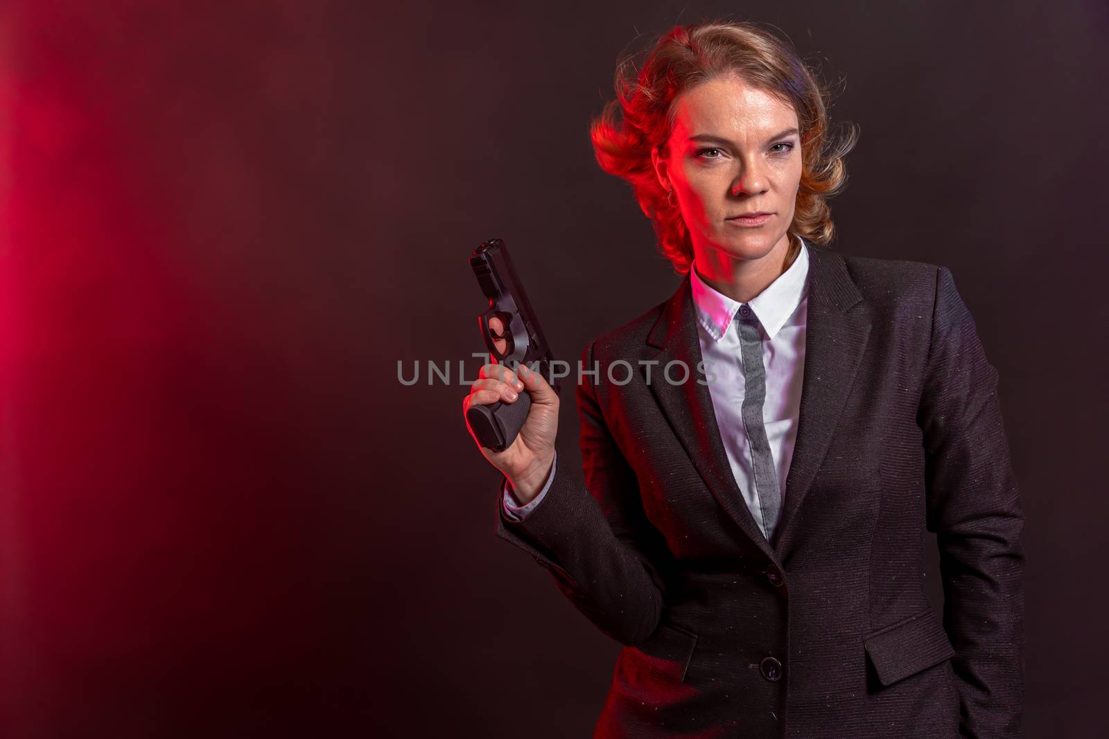 business woman with a gun in his hand. portrait on a black background. copy space by Edophoto