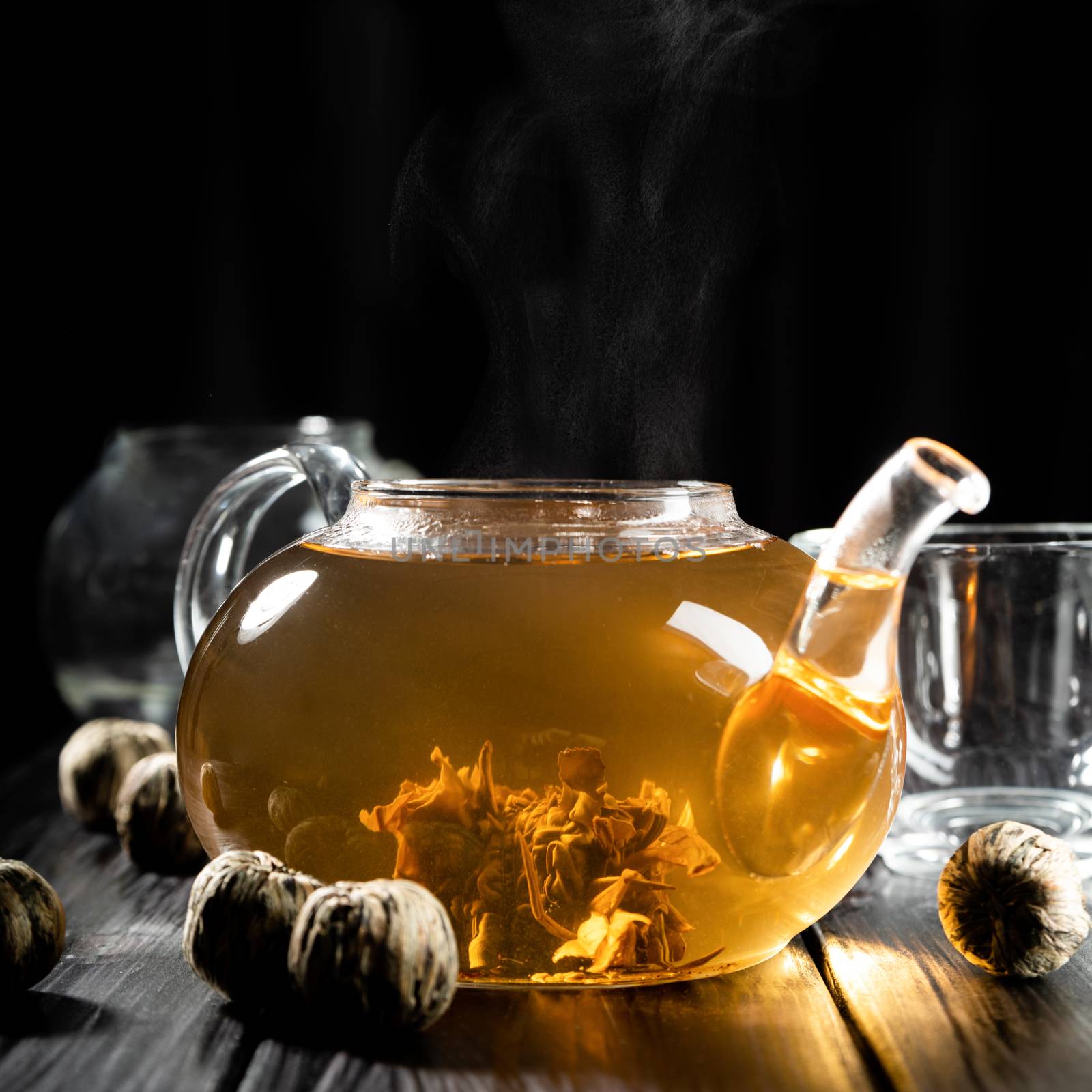 Brewing tea. Glass teapot with hot tea and steam front view dark background