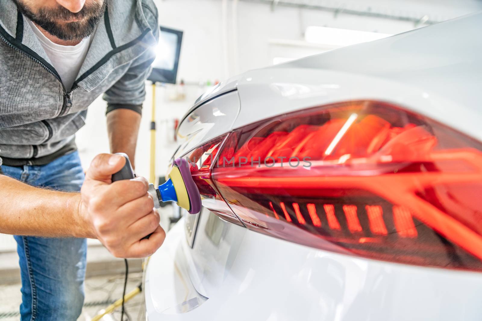 manual polishing of the headlight of luxury cars with the application of protective equipment.