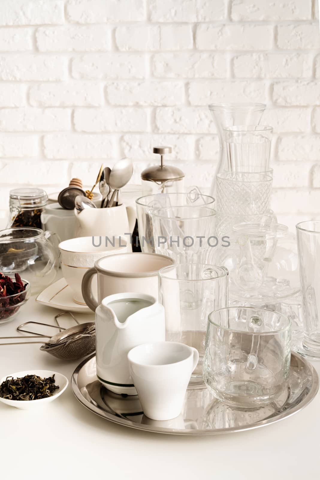 glass and ceramic cups, glasses, glassware for tea on the table on white brick wall background