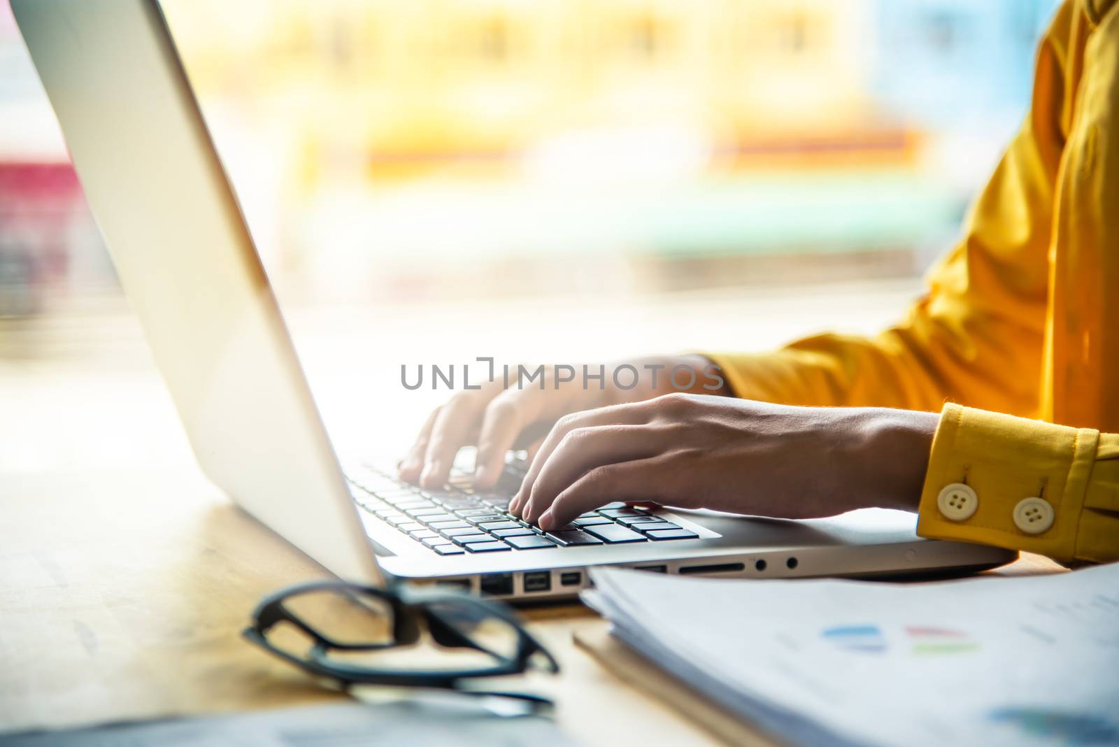 A woman working on a laptop computer at work, with a golden morning light.