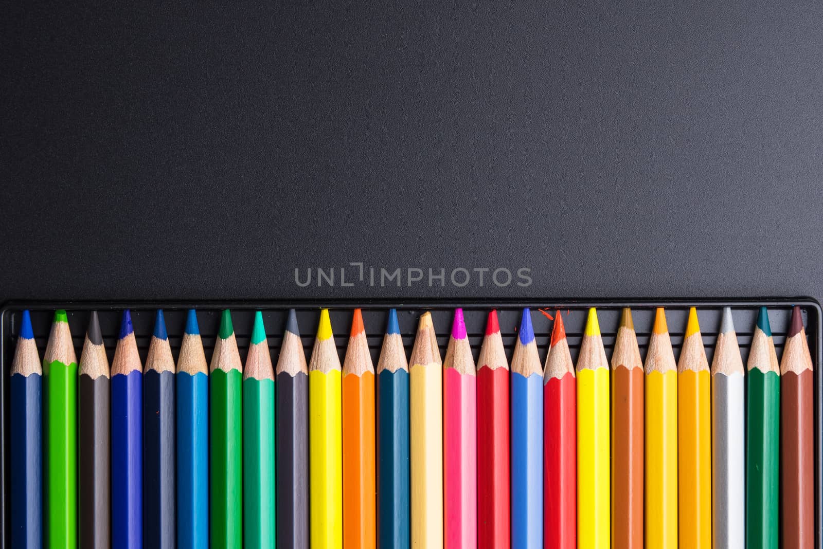 Color Pencils with plastic case isolated on Black Background close up. Colored style view top flat lay with free copy space for design or text. Back to school theme