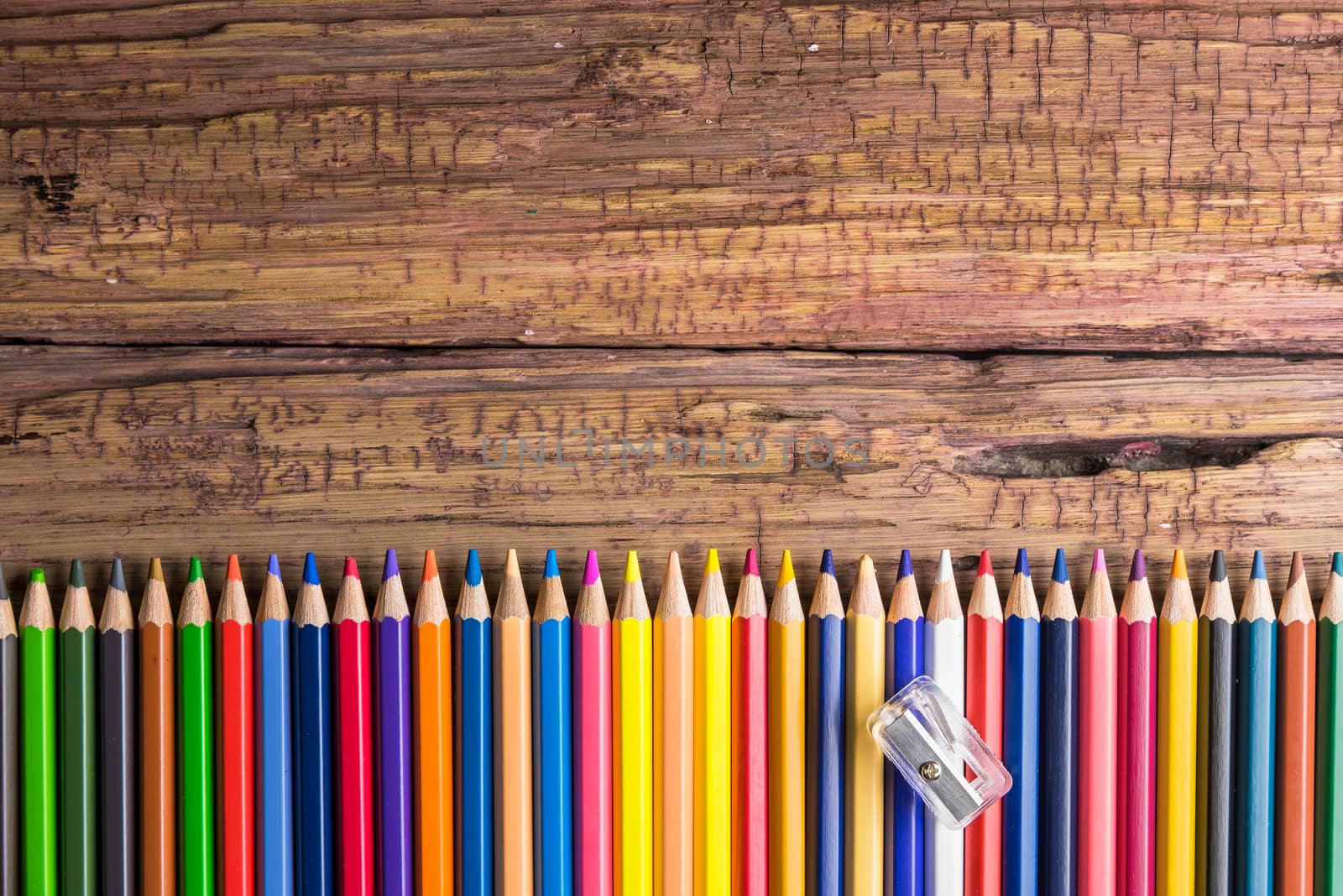 Top view of a set of colored pencils on wooden background with space for your message