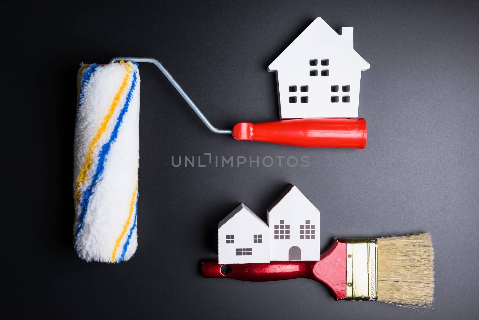 White house toy and paint roller on black background with copy space.Real estate concept, New house concept, Finance loan business concept, Repair maintenance concept