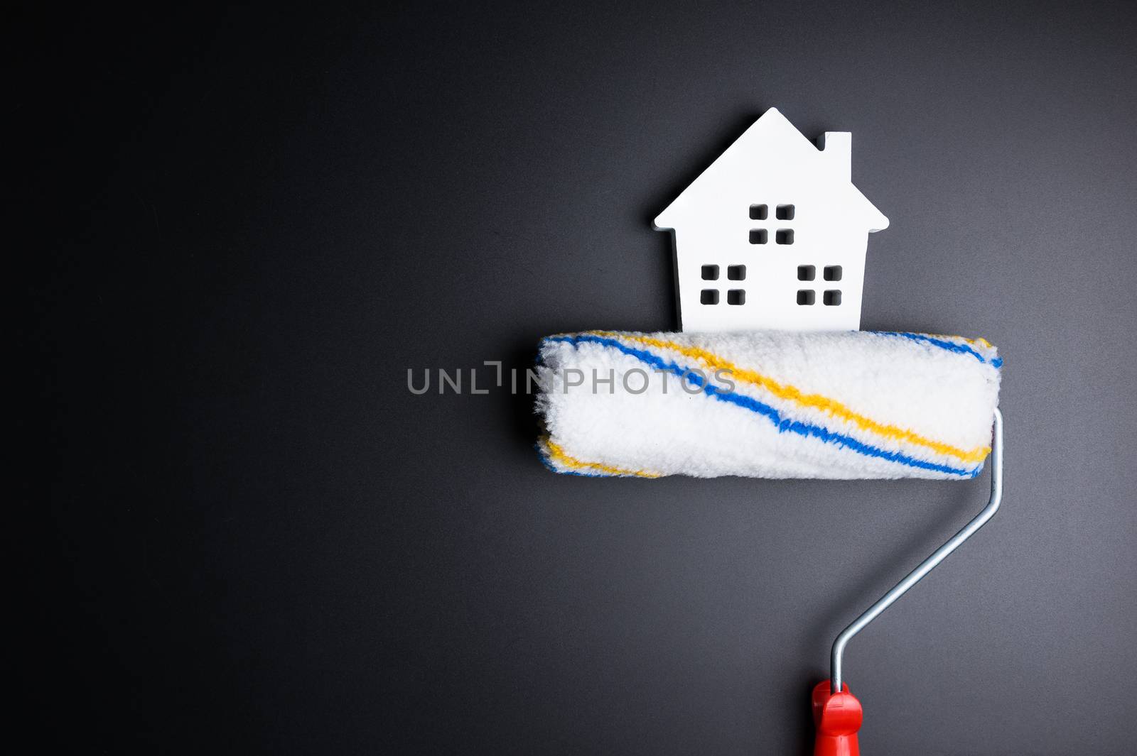 White house toy and paint roller on black background with copy space.Real estate concept, New house concept, Finance loan business concept, Repair maintenance concept