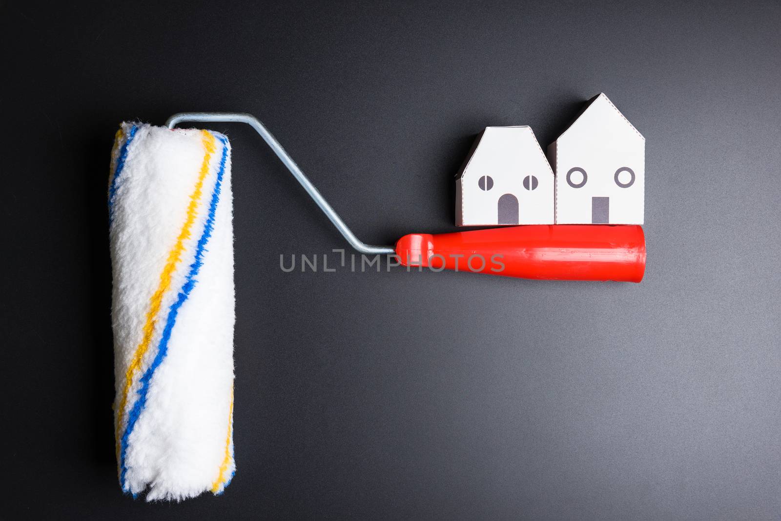 White house toy and paint roller on black background with copy space.Real estate concept, New house concept, Finance loan business concept, Repair maintenance concept