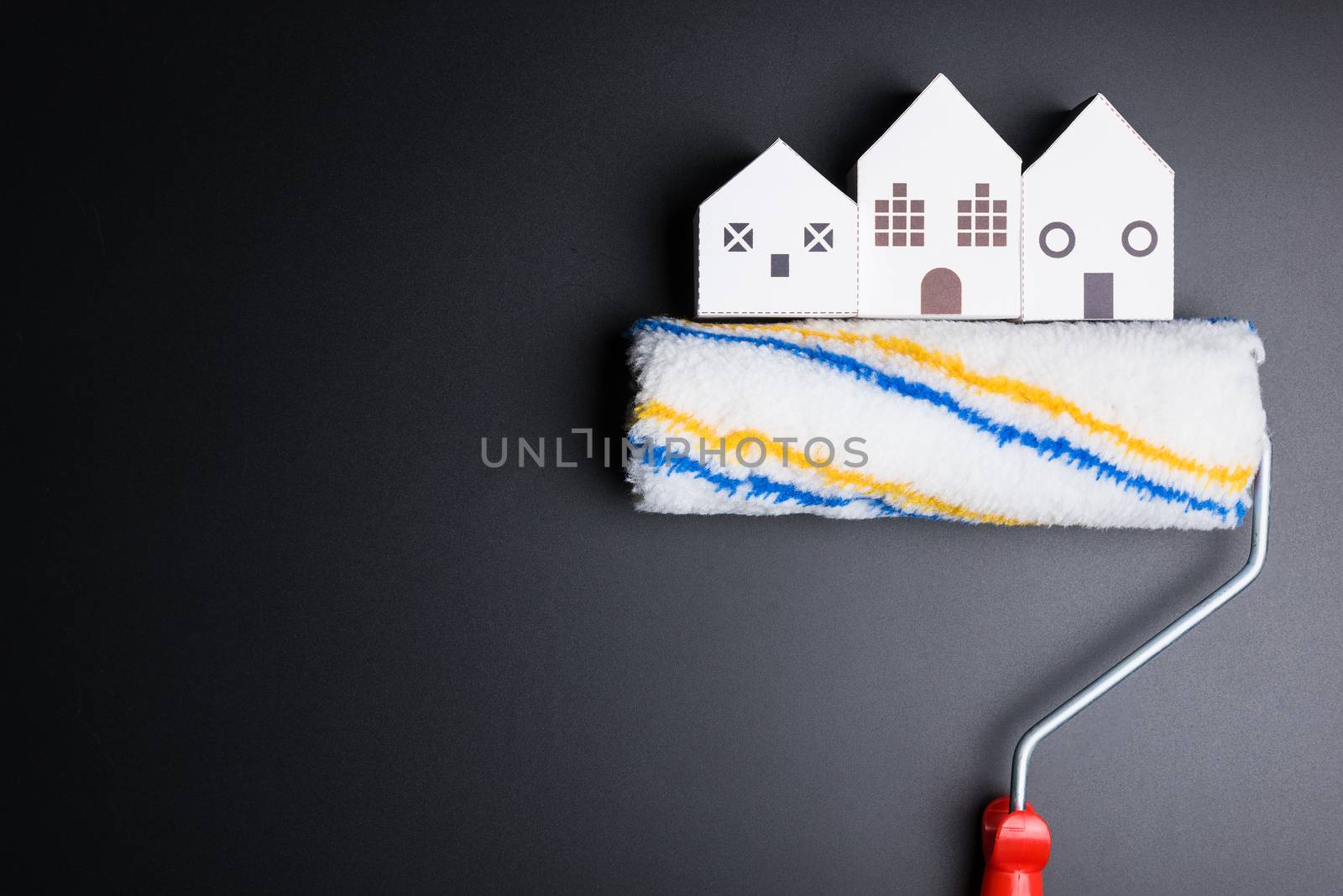 White house toy and paint roller on black background with copy space.Real estate concept, New house concept, Finance loan business concept, Repair maintenance concept