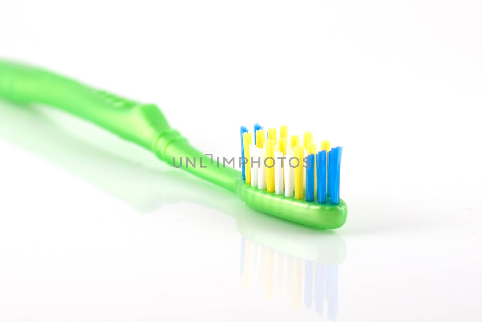 Tooth-brush with green handle over white. Shallow DOF