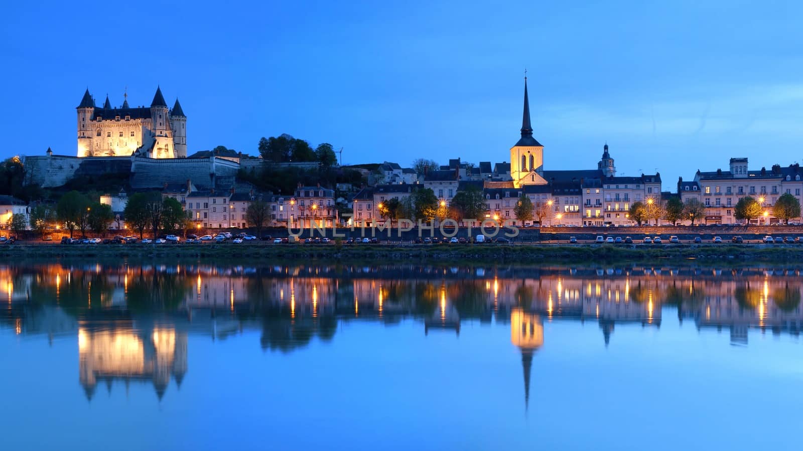 Saumur, France - April 18, 2019: Panorama of Saumur at night with the medieval castle and the old town with Saint-Pierre church, Pays de la Loire, France.