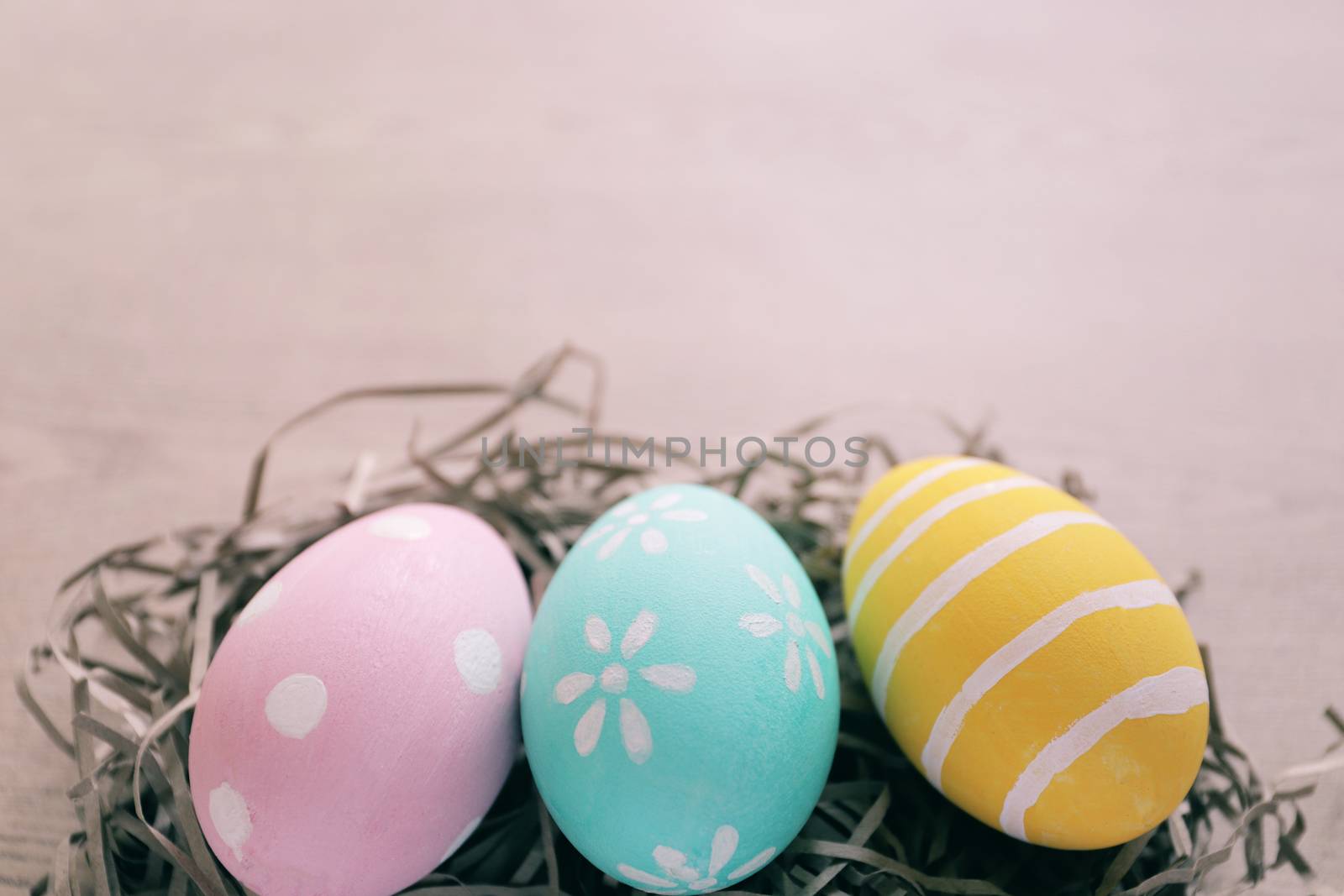 Pastel and colorful easter eggs on nest with wooden background and copy space, happy easter holiday concept