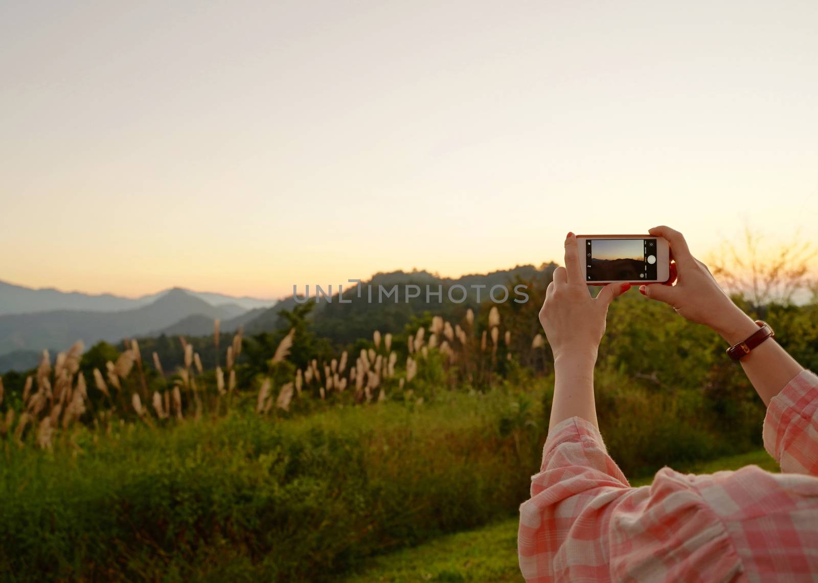 Young asian woman taking a photo with her phone in beautiful mountain view 