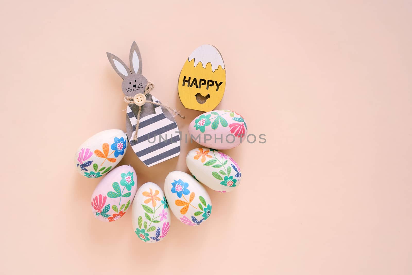 Happy Easter concept with wooden bunny and colorful easter eggs on yellow background. Top view with copy space