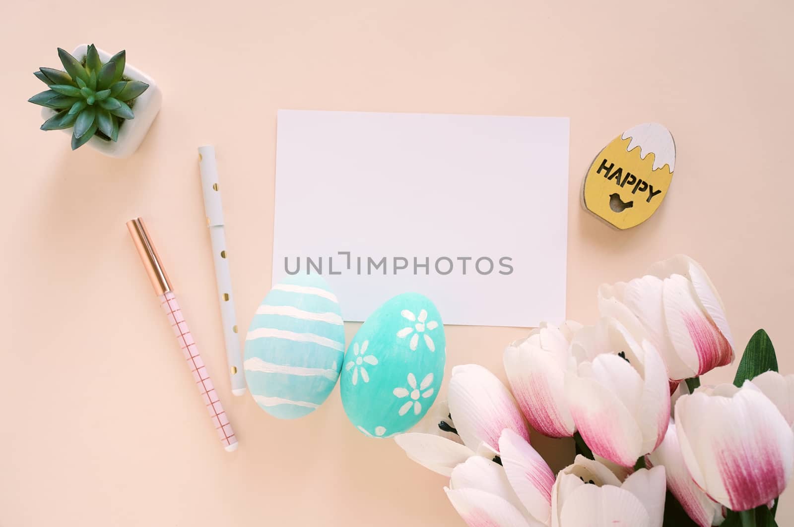 Happy Easter concept with blank card and colorful easter eggs and pink tulips. Top view with copy space