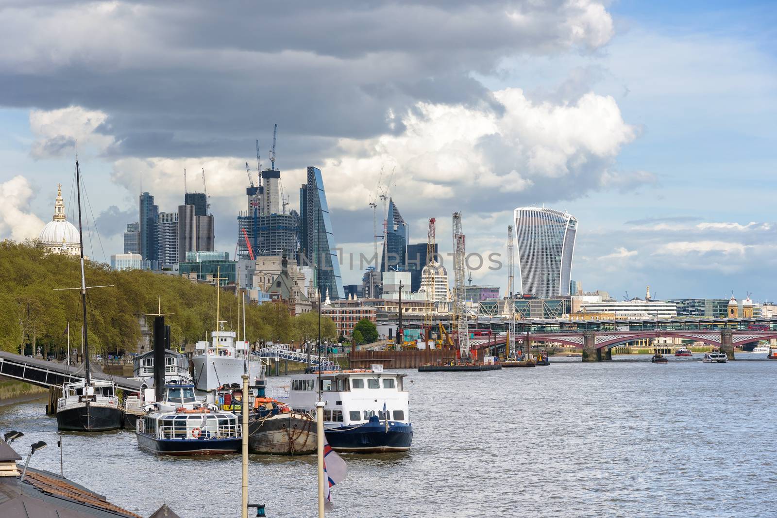 View of ships on Thames River and construction of London city skyscrapers, UK