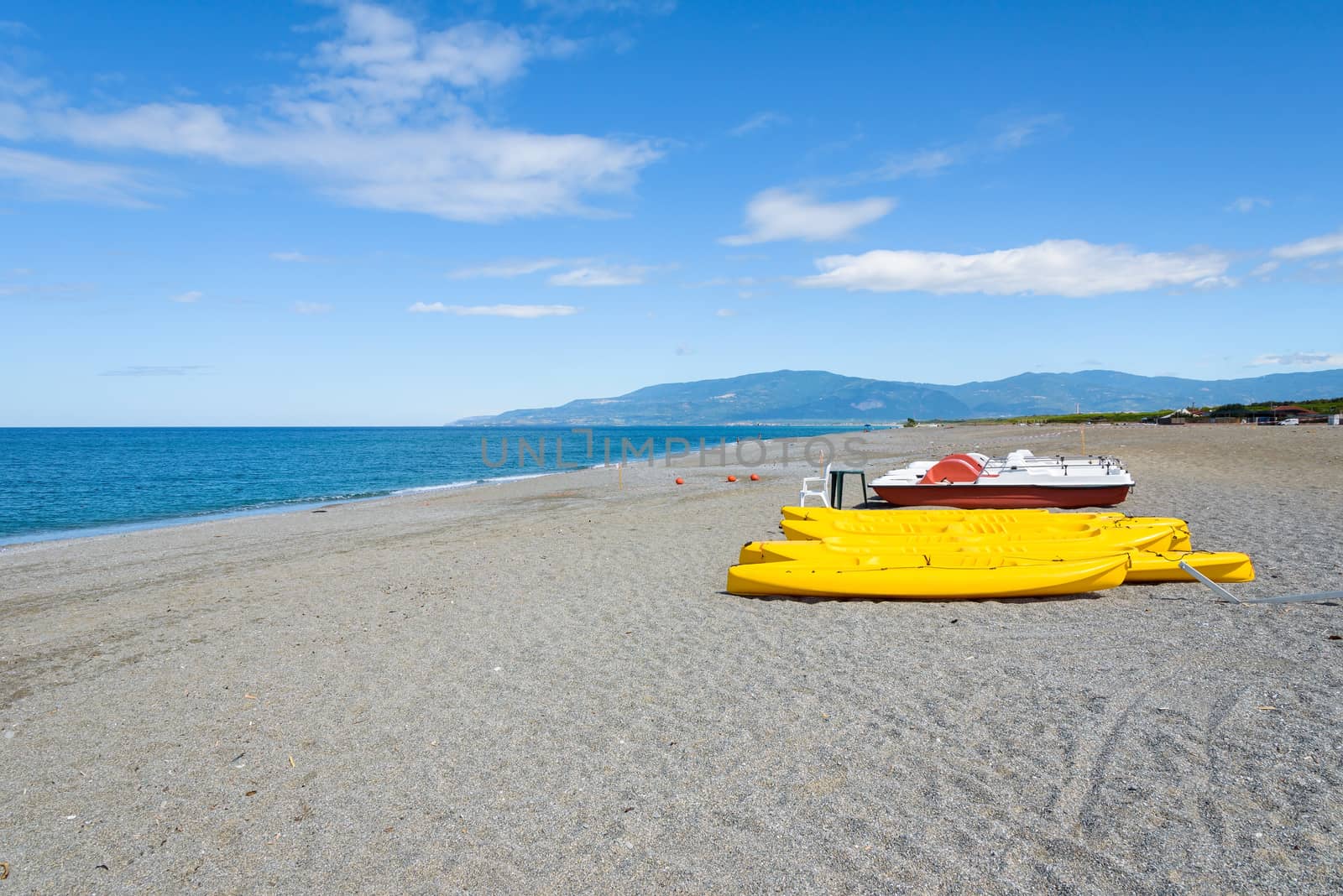 Pedalos and kayaks on a gravel beach by mkos83