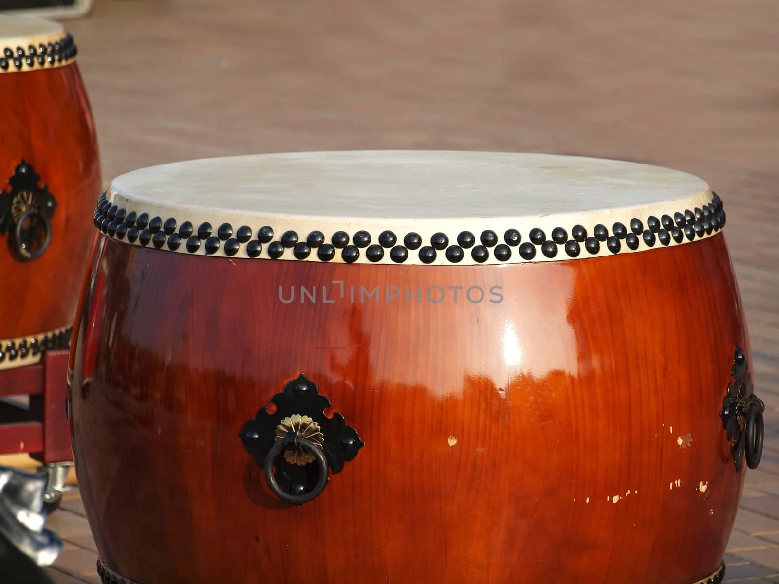 Two large traditional Chinese drums with brass handles and black tacks
